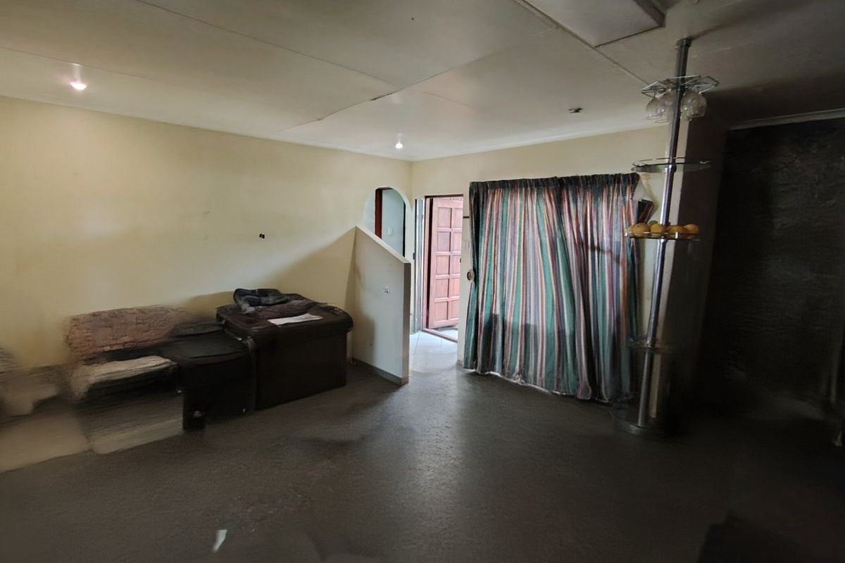A living room area featuring an archway, half-wall partition, and timber entrance door, requiring cosmetic updates and ceiling repairs.