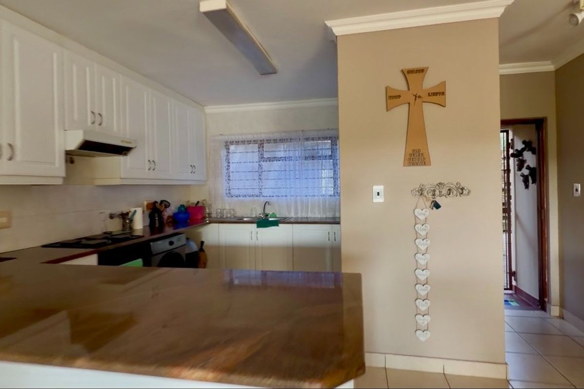 A functional kitchen featuring white cabinetry, laminate countertops, a built-in hob with extractor fan, and tiled flooring, offering a practical layout for daily use.