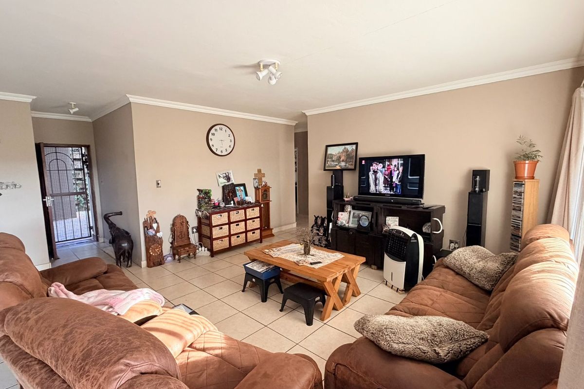 Spacious living room featuring neutral wall tones, tiled flooring, and decorative cove cornicing, providing a comfortable and functional family area.