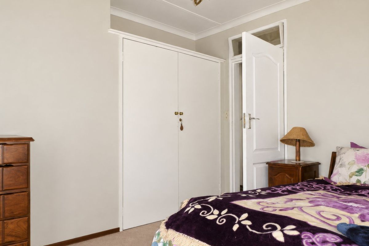 A bedroom featuring neutral walls, carpet flooring, a built-in wardrobe, and a classic door with a transom window above.