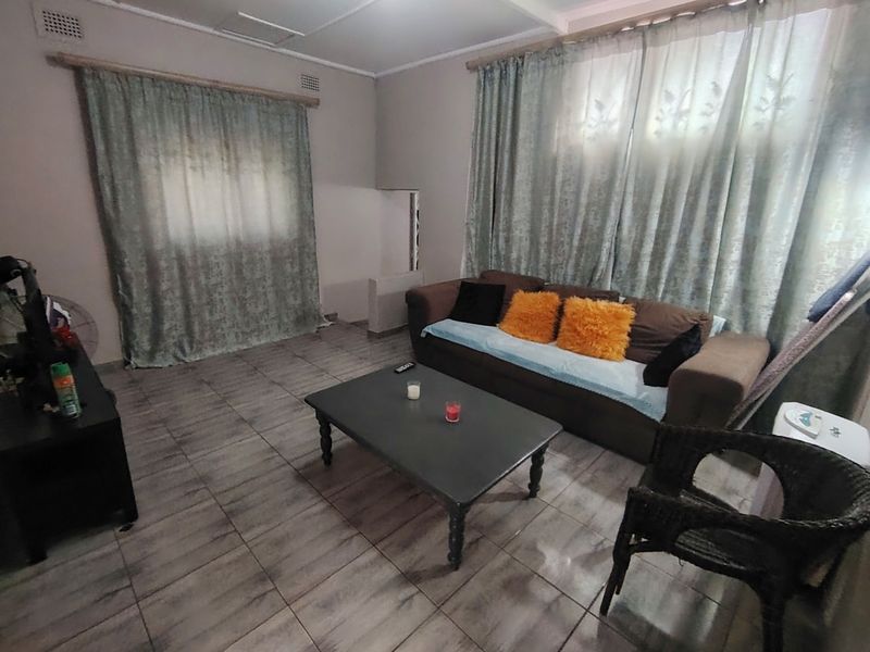 A living room featuring tiled flooring and dual window treatments, providing a functional space for relaxation.