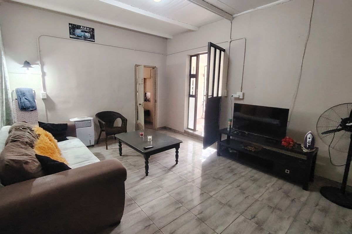 A living room featuring tiled flooring and exposed beam ceilings, with direct access to an external area.