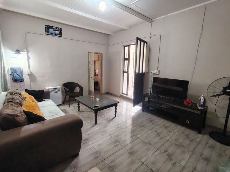 A living room featuring tiled flooring and exposed beam ceilings, with direct access to an external area.