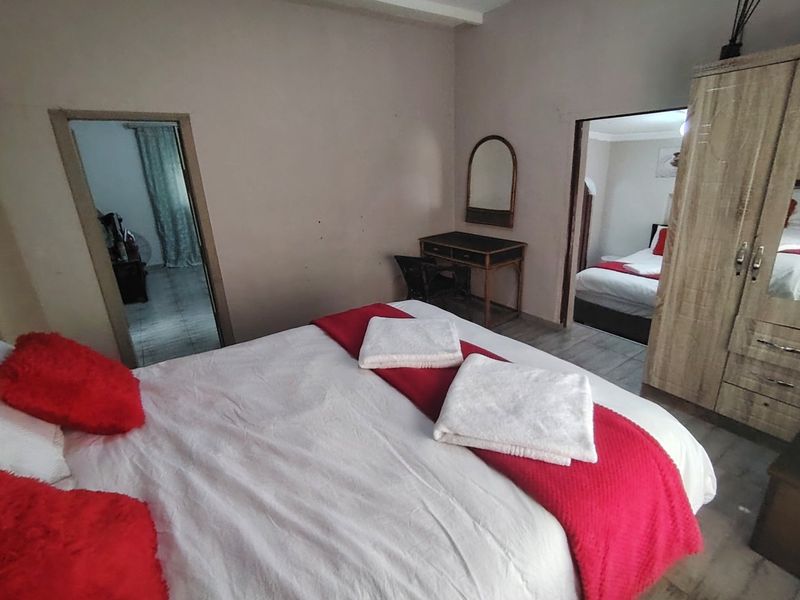 A bedroom featuring tiled flooring and a built-in wardrobe, with access to adjacent rooms through open doorways.