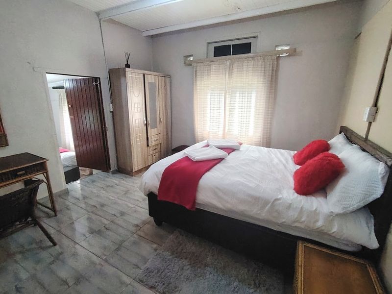 A bedroom featuring tiled flooring and a built-in wardrobe, showing signs of wear and requiring cosmetic updates to improve its overall condition.