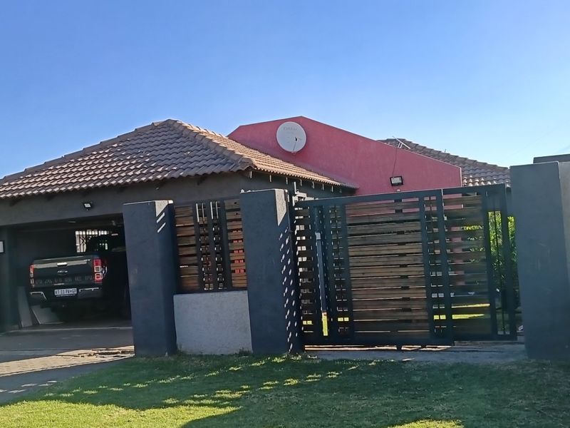 Front view of a residential property featuring a tiled roof, a modern sliding gate, and a covered carport area.