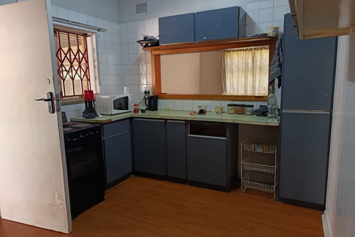 A dated kitchen featuring blue cabinetry, laminate countertops, and tiled splashbacks, offering significant potential for modernization and renovation.