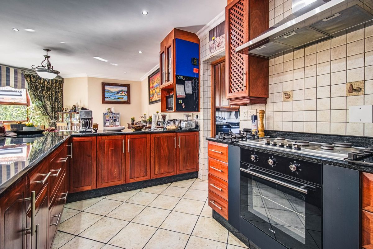 A functional kitchen featuring dark wood cabinetry, granite countertops, a built-in oven with gas hob, and tiled flooring, offering a classic layout.