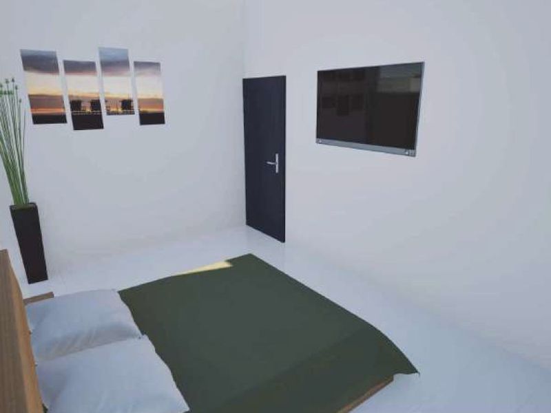 A simple bedroom interior featuring white walls and a dark door.