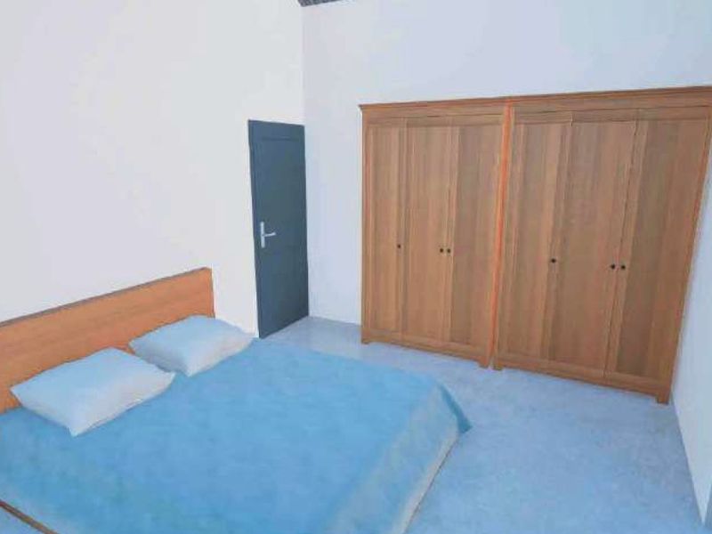 A bedroom featuring built-in wooden wardrobes and high ceilings, providing a functional space with neutral finishes.