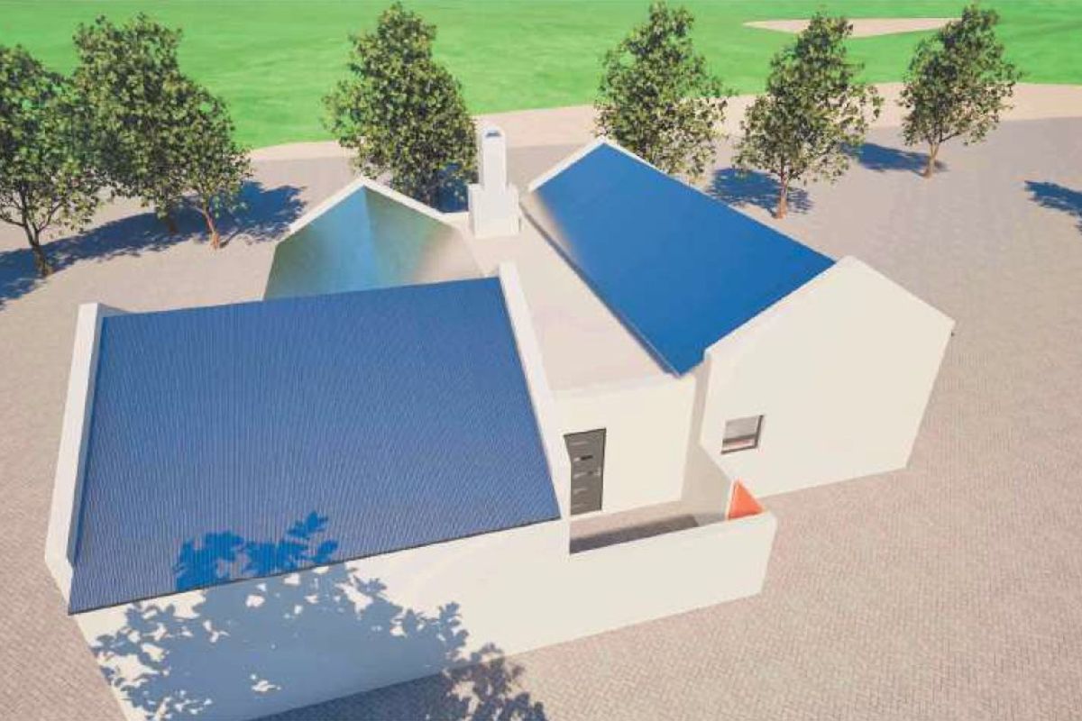 An aerial view of a residential property featuring a pitched roof design, a central chimney, and surrounding paved grounds.