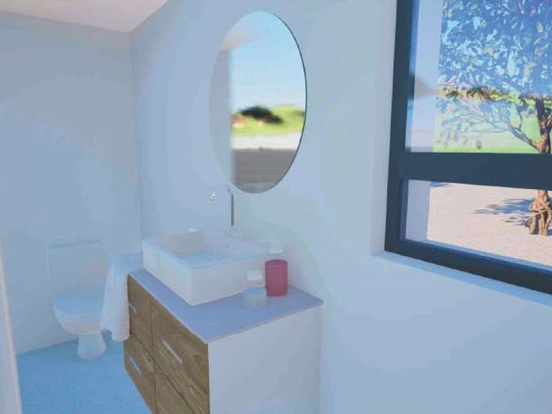 A modern bathroom featuring a wood-finish vanity with a vessel sink, a circular mirror, and a toilet, illuminated by a large window.