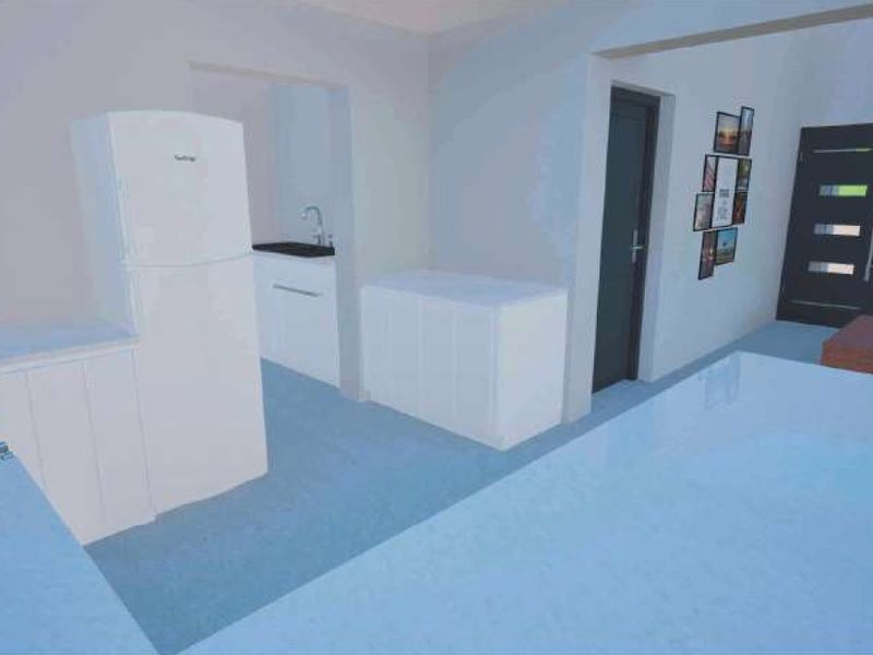An open-plan kitchen and living area featuring white cabinetry, a gas hob, and direct access to the entrance.