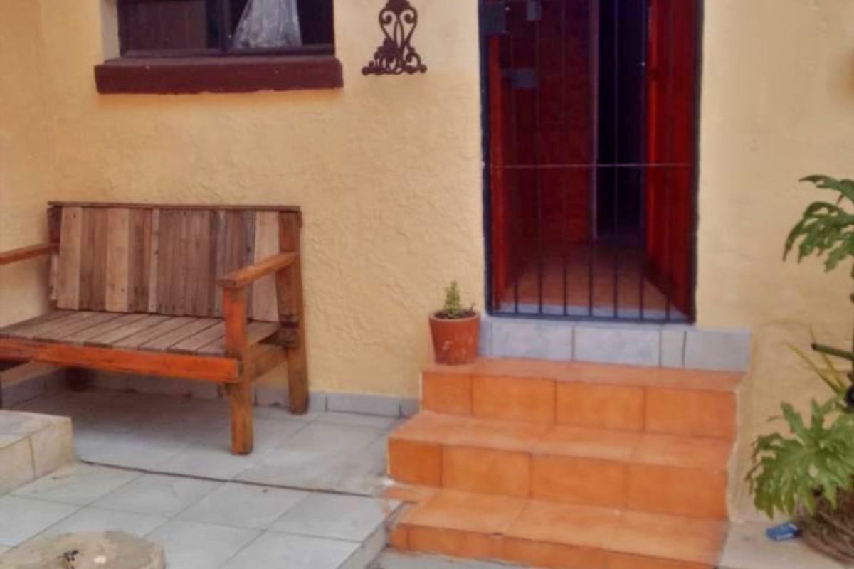 Rear exterior view of the apartment featuring a tiled patio area, security gate entrance, and external satellite dish installation.