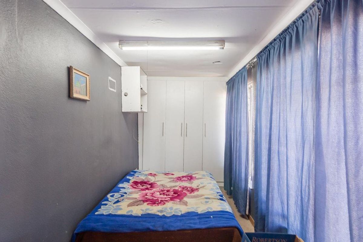 A bedroom featuring built-in cupboards and a fluorescent light fixture, requiring cosmetic updates to improve the overall condition of the finishes.