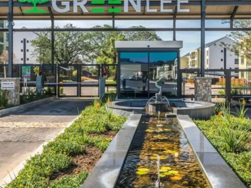 The main entrance to the Greenlee estate featuring a secure gatehouse, modern water feature, and well-maintained landscaped gardens.