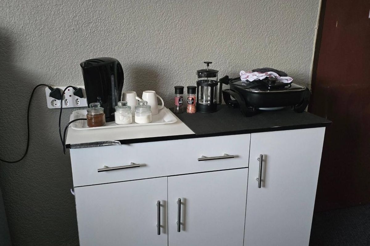 A compact kitchen unit featuring white cabinetry and a black countertop, providing functional storage and preparation space.