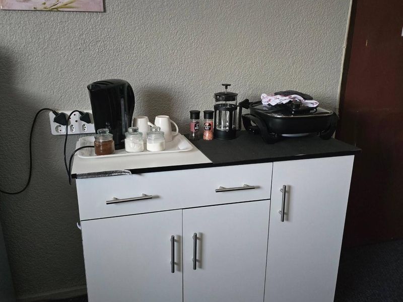 A compact kitchen unit featuring white cabinetry and a black countertop, providing functional storage and preparation space.