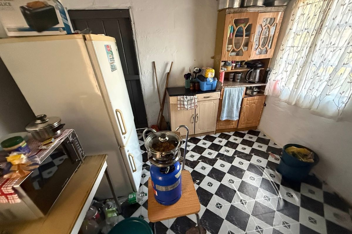 A compact kitchen featuring traditional cabinetry and a distinctive checkered tile floor, offering potential for a modern renovation.