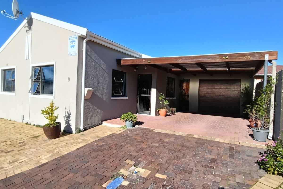 Front exterior view of the property featuring a paved driveway, covered carport, and secure garage access.