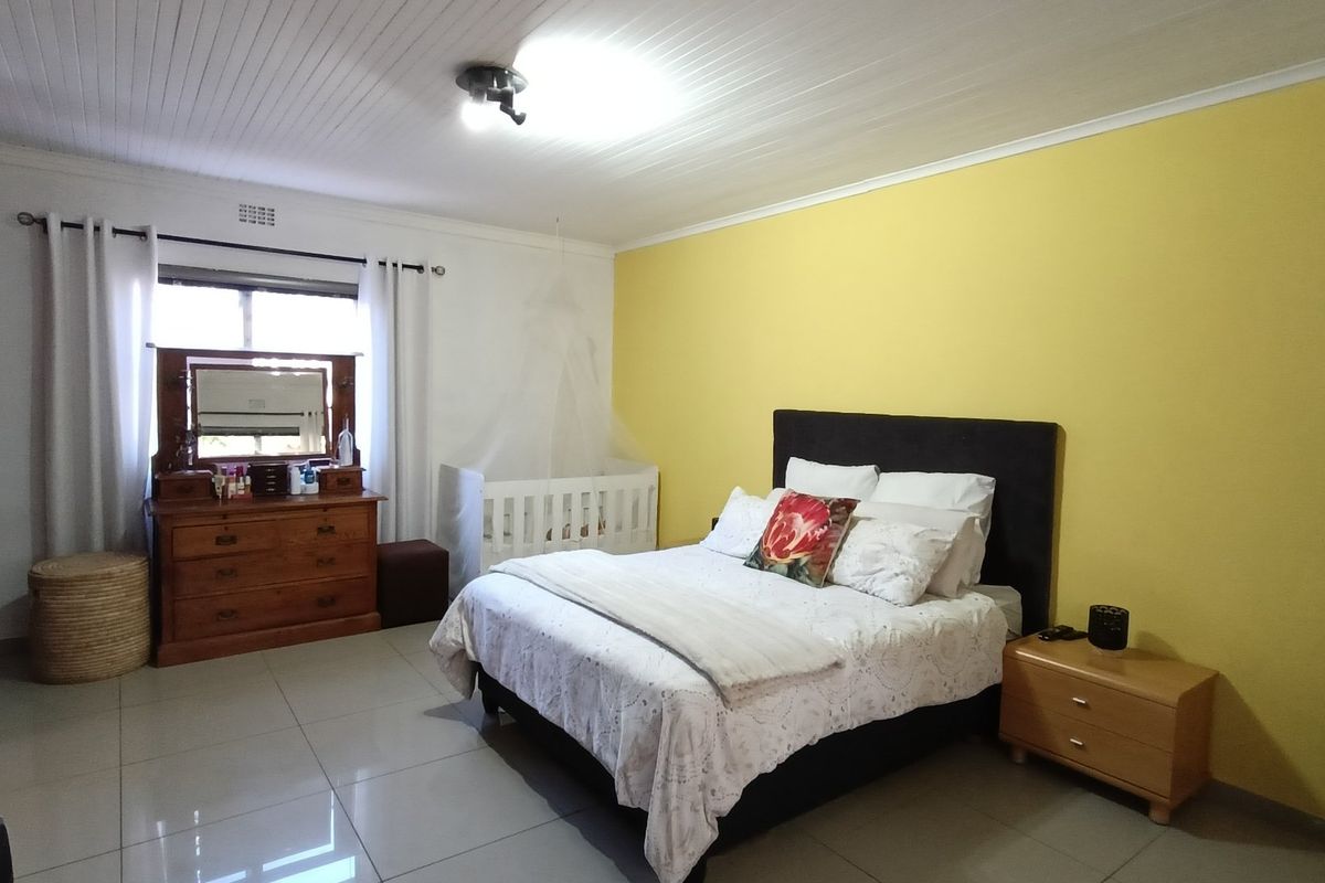Spacious bedroom featuring tiled flooring and a classic tongue and groove ceiling, offering a bright and functional living space.