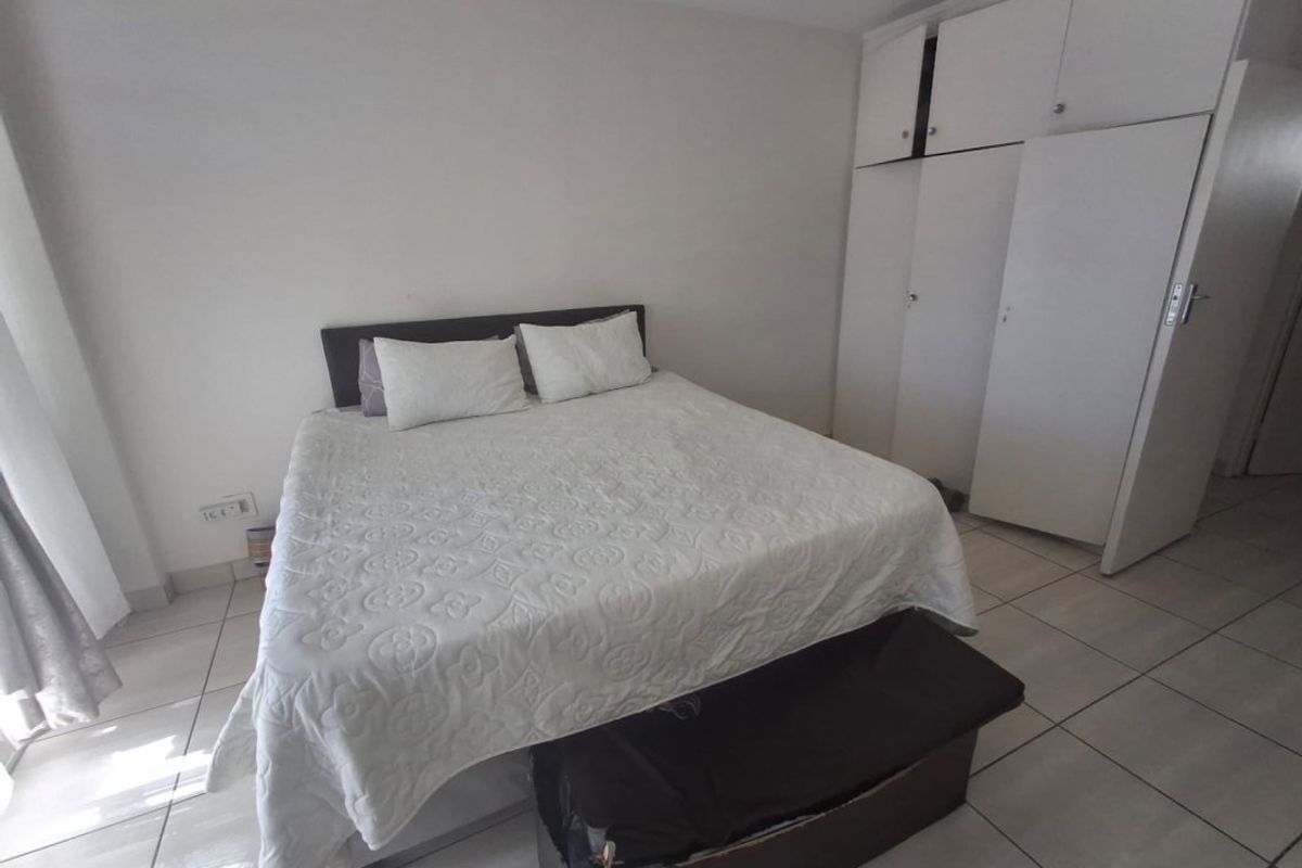 A bedroom featuring neutral walls, tiled flooring, and built-in storage cupboards.