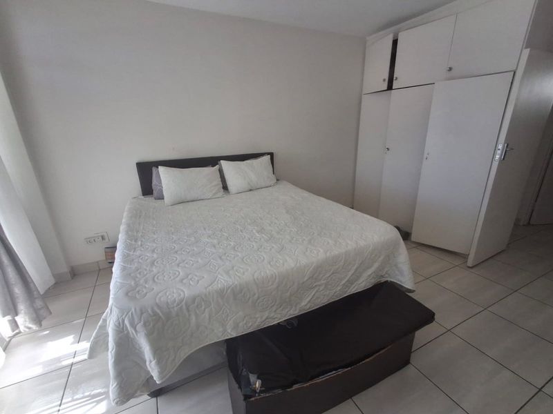 A bedroom featuring neutral walls, tiled flooring, and built-in storage cupboards.