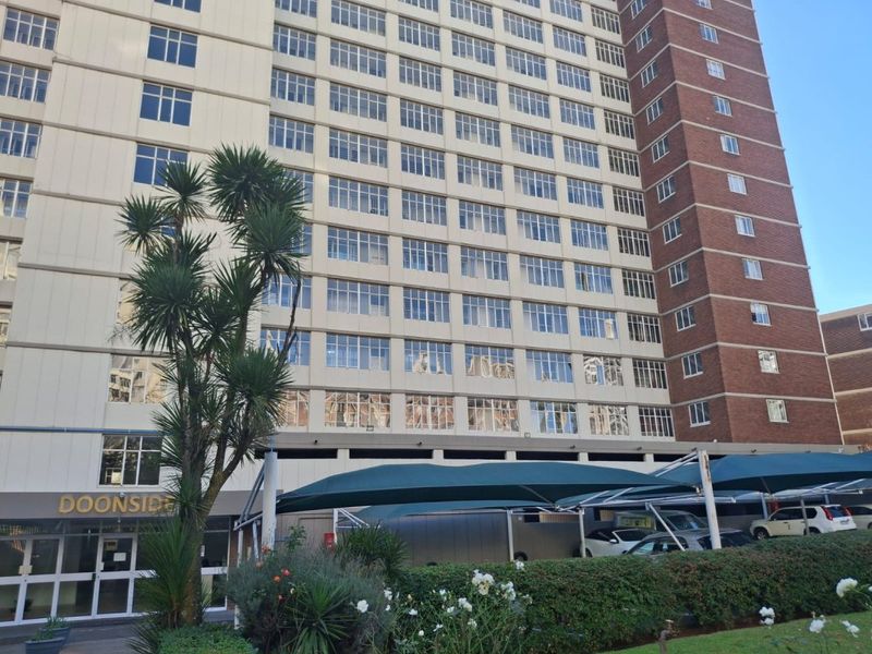 Exterior view of the Doonside apartment building featuring a multi-story facade with brick and concrete finishes, grid windows, and covered parking bays.