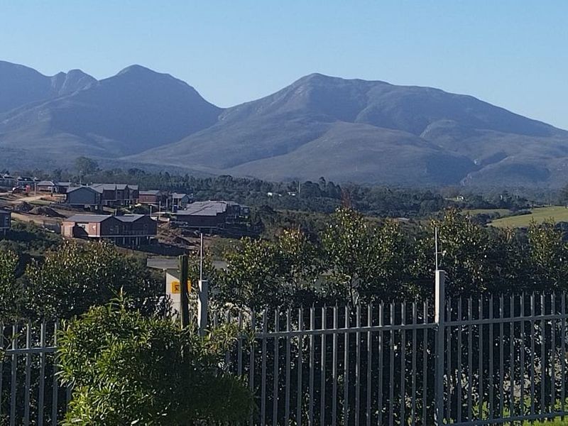 Scenic elevated view of the surrounding landscape and mountain range, featuring secure perimeter fencing in the foreground.