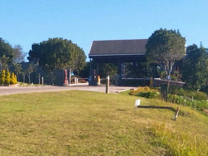 View of the residential estate entrance featuring a security gatehouse, boom gate, and well-maintained landscaped surroundings.