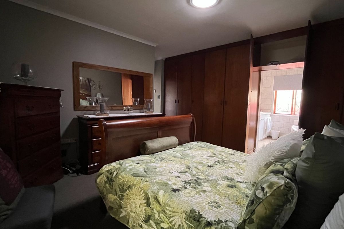 A bedroom featuring extensive built-in wooden cabinetry and direct access to an adjoining bathroom area.