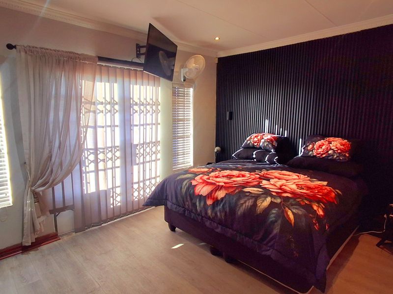 A well-maintained bedroom featuring a modern slatted accent wall, laminate flooring, and direct access to an outdoor area through a sliding door.