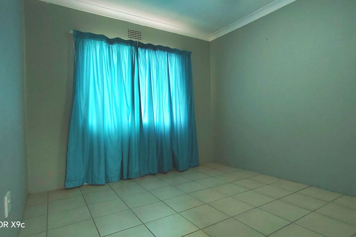 A vacant bedroom featuring neutral wall paint, tiled flooring, and classic ceiling cornicing, providing a clean and versatile space ready for personalization.
