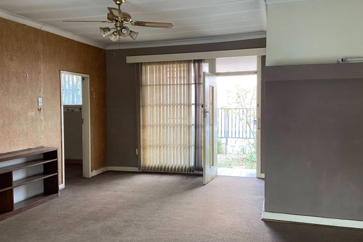 Spacious living room featuring built-in shelving, a ceiling fan, and direct access to the outdoor area through a glass door.