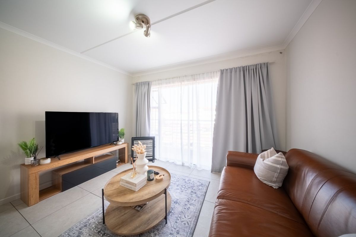A bright living room featuring neutral tiled flooring and a large sliding glass door that provides access to the outdoor area.
