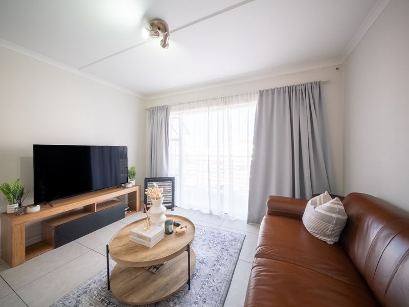 A bright living room featuring neutral tiled flooring and a large sliding glass door that provides access to the outdoor area.