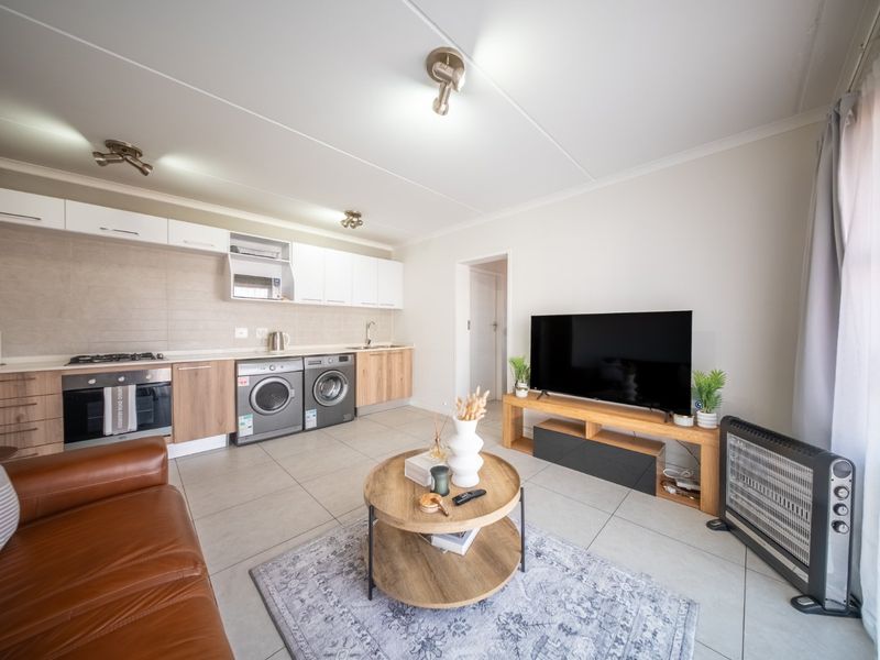 Modern open-plan living area featuring a well-equipped kitchen with built-in cabinetry, integrated oven, gas hob, and sleek tiled flooring throughout.