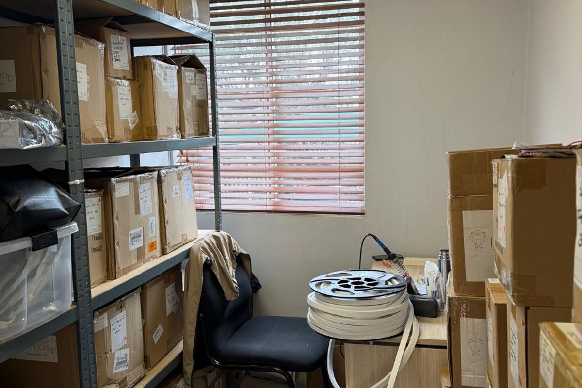 A functional utility or storage room featuring tiled flooring, a suspended ceiling, and a window with venetian blinds.