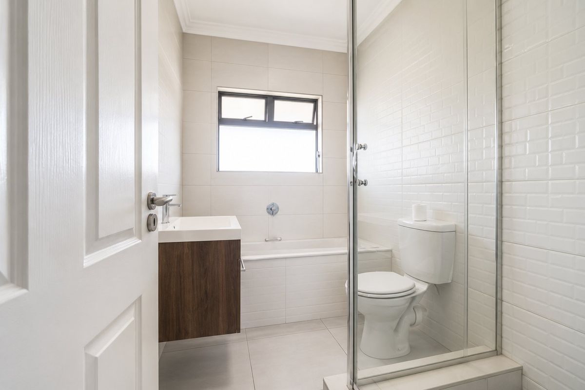 A modern bathroom featuring a wall-mounted vanity, a built-in bathtub, and a glass-enclosed shower with white subway tile finishes.