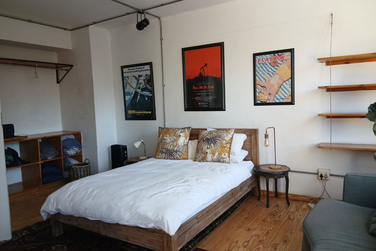 A bedroom featuring industrial-style exposed conduit and piping, timber flooring, and built-in shelving units.