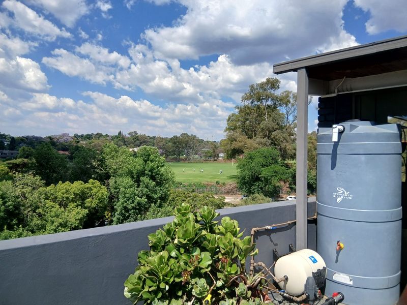 A balcony area featuring a water storage tank and pressure pump system, offering an elevated view over the surrounding neighborhood and green space.