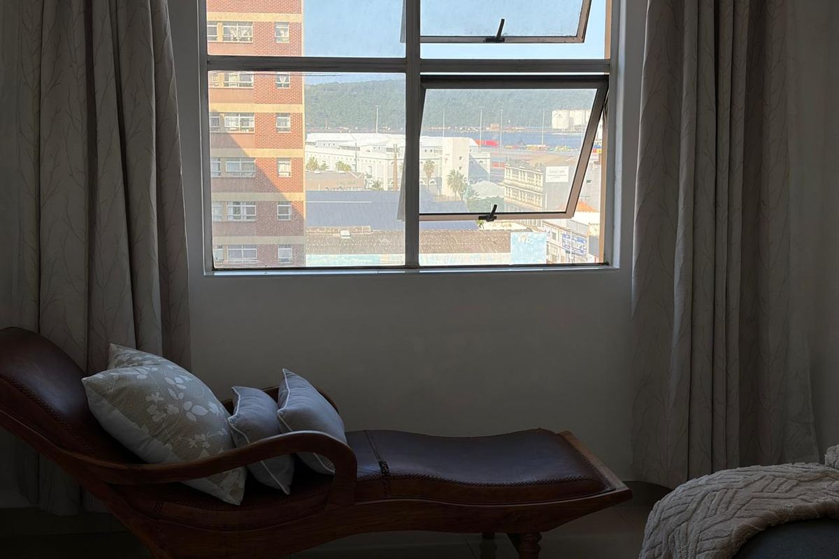 A bedroom featuring a large window with views of the surrounding urban area and harbour.