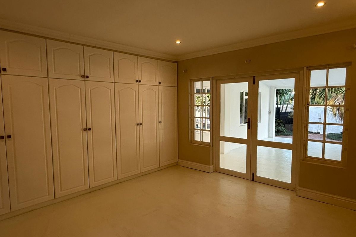 Spacious bedroom featuring extensive built-in cabinetry, recessed lighting, and direct access to an outdoor patio area through glass-paned french doors.