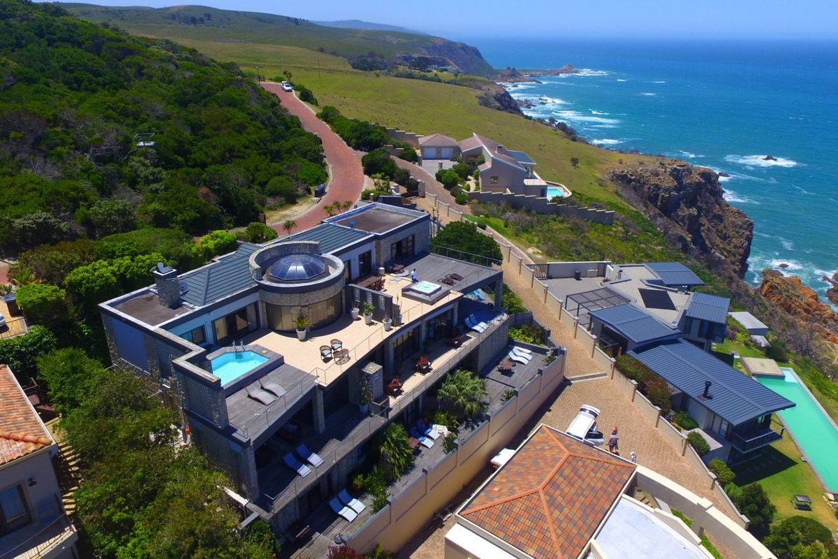 Aerial view of a coastal luxury property featuring multiple terraces, a swimming pool, and expansive ocean views.