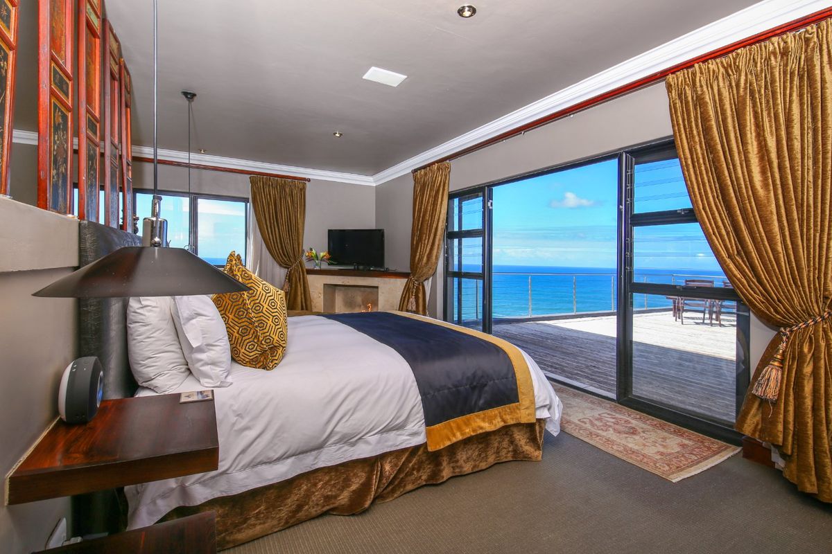 Spacious bedroom featuring crown molding, recessed lighting, a built-in fireplace, and large sliding glass doors opening onto a balcony with expansive ocean views.
