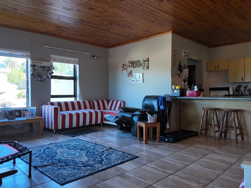 Open plan living area featuring tiled floors, a timber ceiling, and a functional kitchen with a breakfast bar.