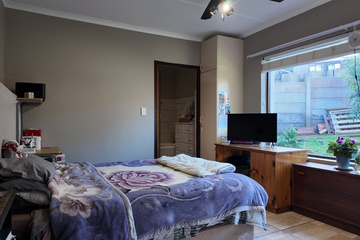 A functional bedroom featuring tiled flooring, a built-in cupboard, and a ceiling fan, with direct access to an en-suite bathroom.