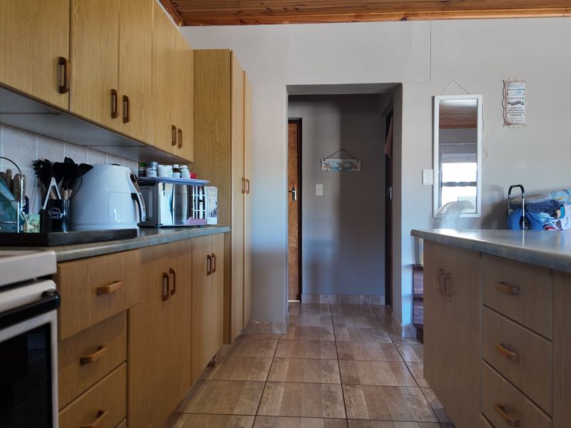 A functional kitchen featuring laminate cabinetry, tiled flooring, and a timber ceiling, providing a practical layout with ample storage space.