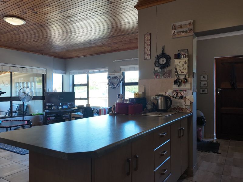 Open plan living area featuring a kitchen island with laminate countertops, tiled flooring, and a distinctive timber tongue and groove ceiling.