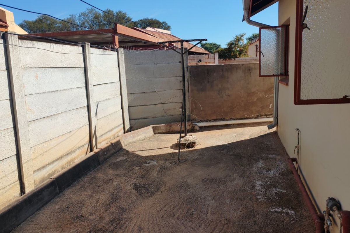 A rear exterior courtyard area featuring precast concrete boundary walls and concrete paving, requiring maintenance and potential landscaping to improve the outdoor space.